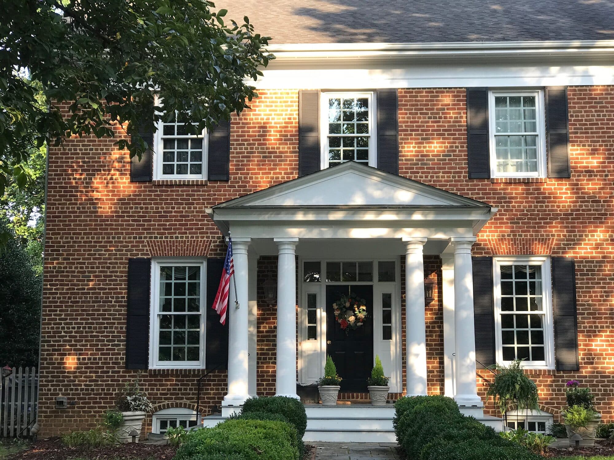 Freshly painted white portico columns and trim on a brick home, exterior painting by Percy Dillard Painting & Drywall