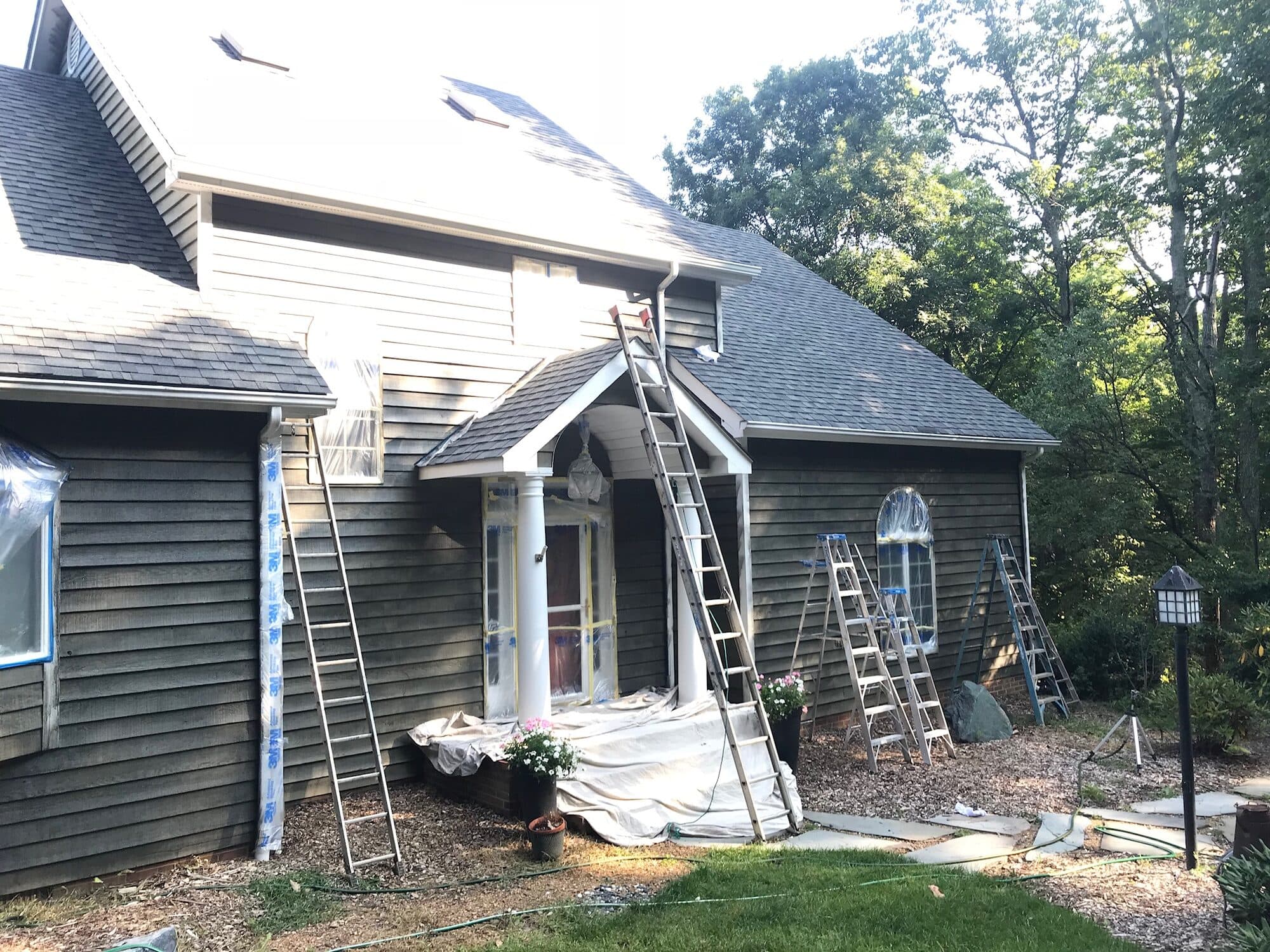 Percy Dillard Painting & Drywall crew painting a home's exterior, with windows and doors masked off to protect them